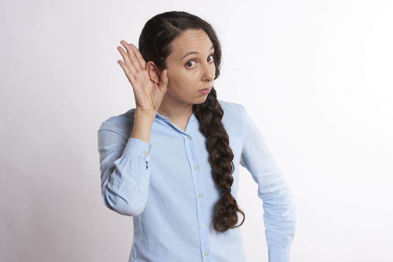 woman holding hand up to ear to listen