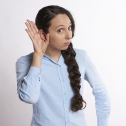 woman holding hand up to ear to listen