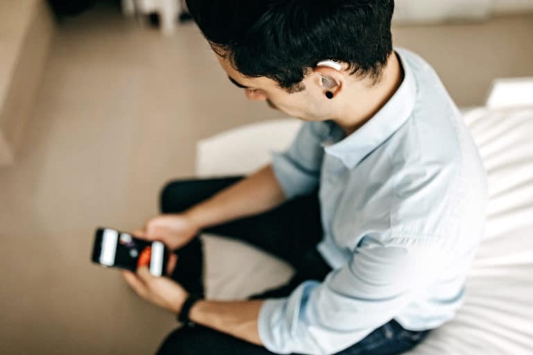 Relaxed Businessman Using Phone in Hotel Room wearing a hearing aid