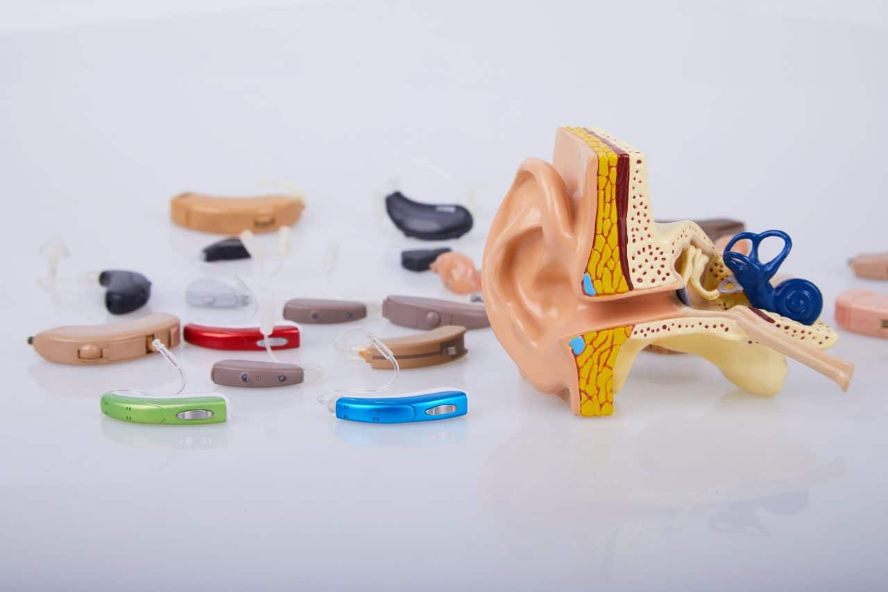 Collection of hearing aids next to ear model.
