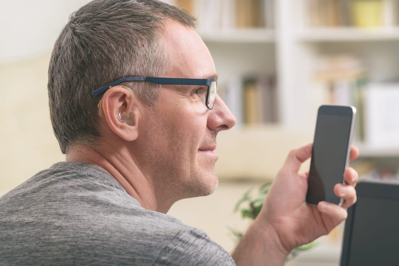 Man with hearing aid uses a phone.