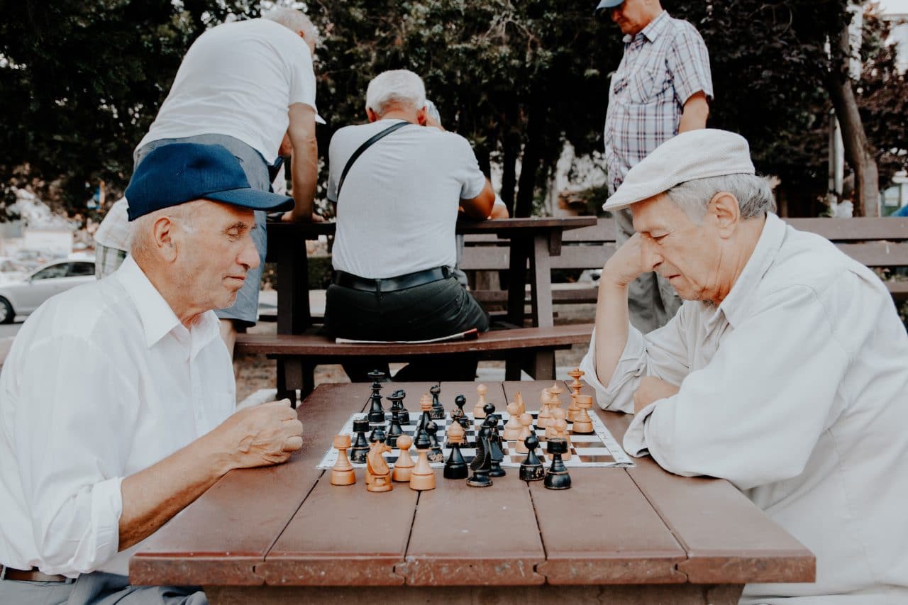 Two older men playing chess outside.