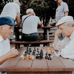 Two older men playing chess outside.