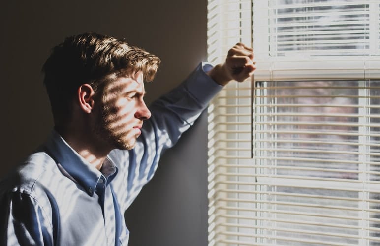 A lonely looking man staring out of a window.