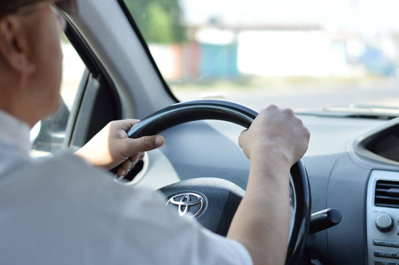 Close up of man driving with hands on the steering wheel.