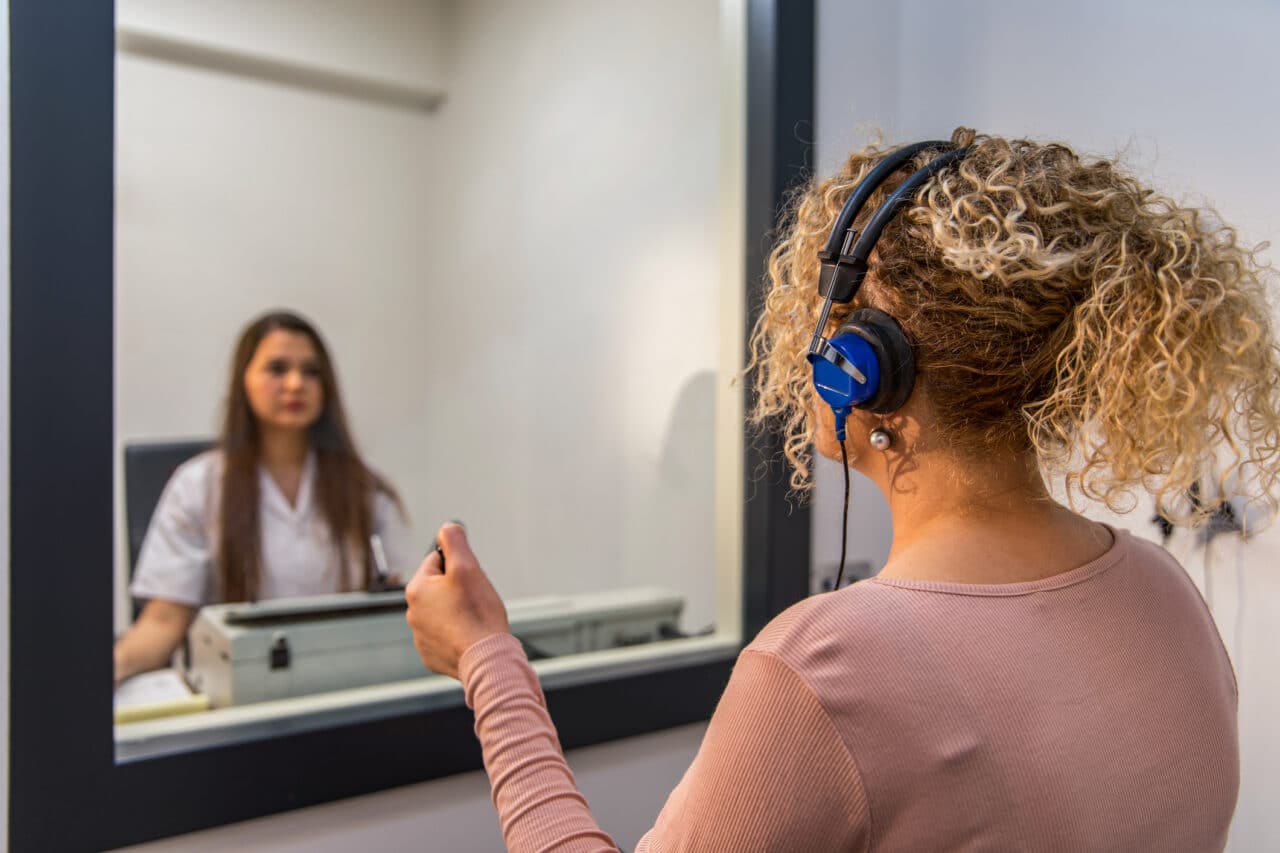 Woman sitting in a sound test booth audiologist office