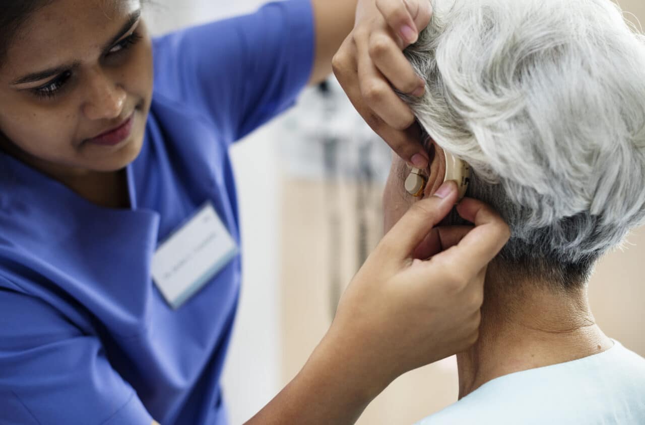 An older woman being fitted for a hearing aid.