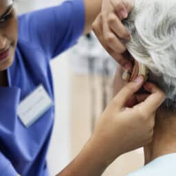 An older woman being fitted for a hearing aid.