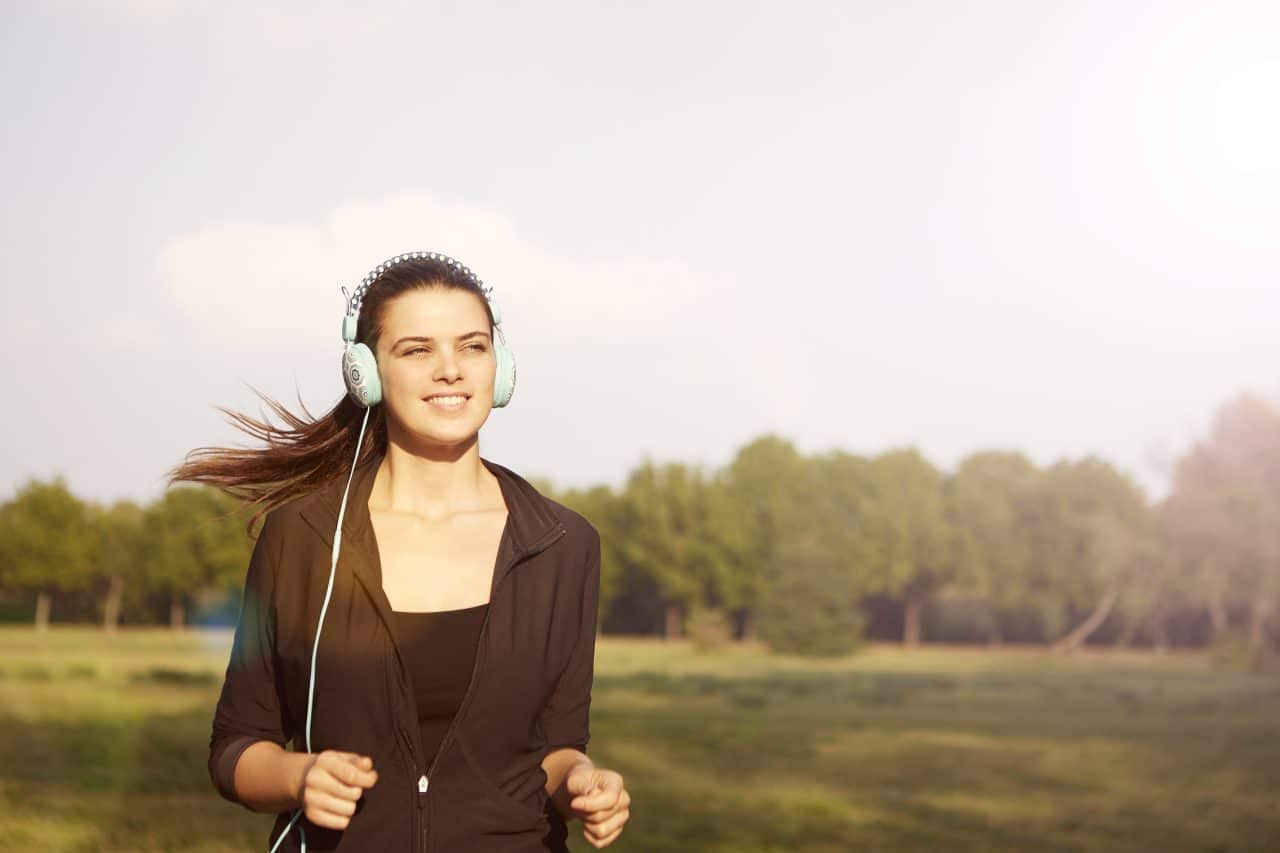 Woman listening to headphones outside.