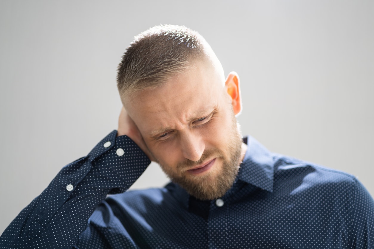 Man experiencing tinnitus holding his ears looking upset.