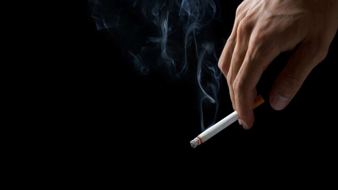 Close up of a man holding a cigarette