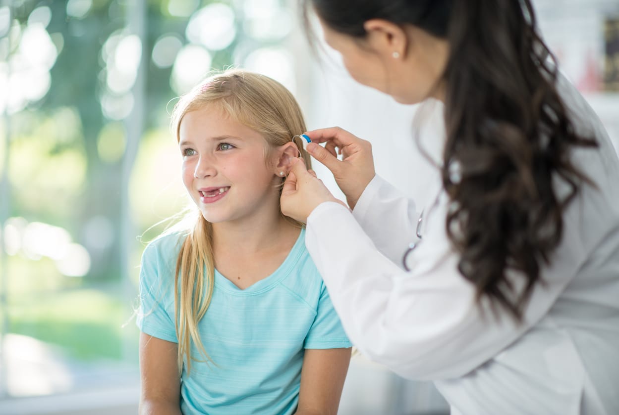 Young girl being fit for a hearing aid.