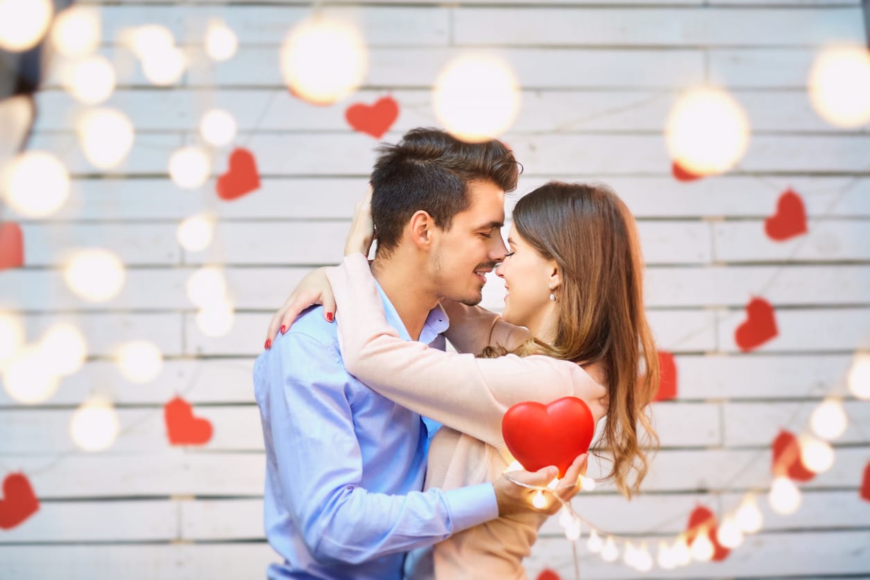 Young couple surrounded by hearts and lights.