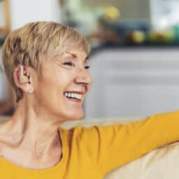 A happy woman wearing a new hearing aid.