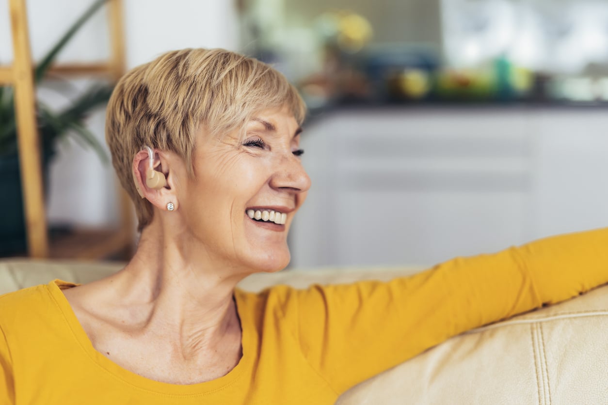 A happy woman wearing a new hearing aid.